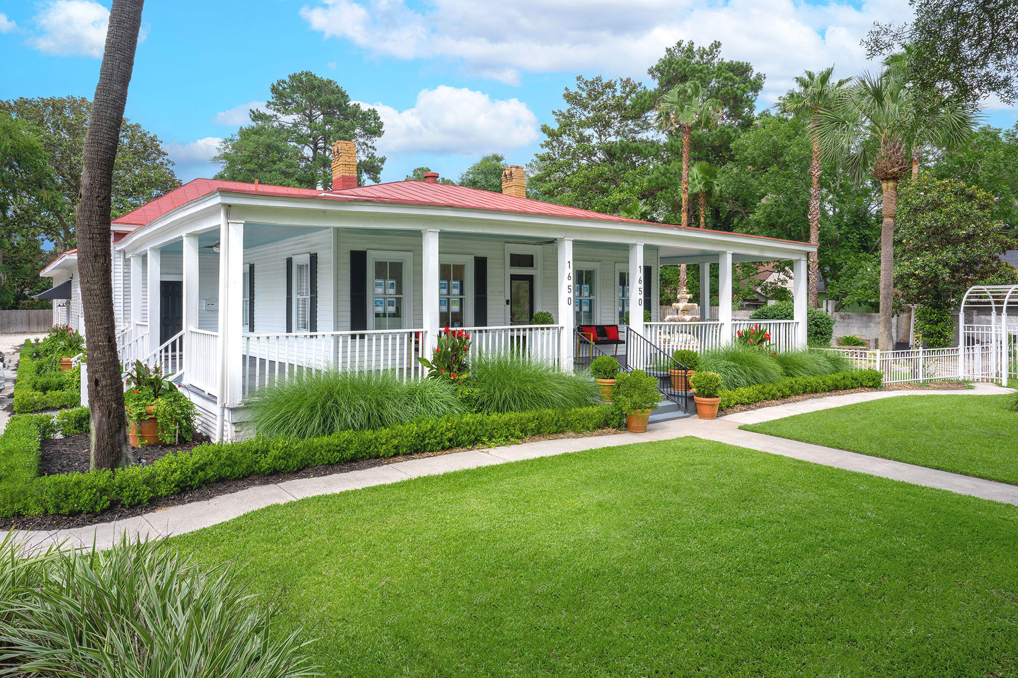 Mopper Property Management office — a white cottage with a red metal roof and wraparound porch in Savannah, Georgia